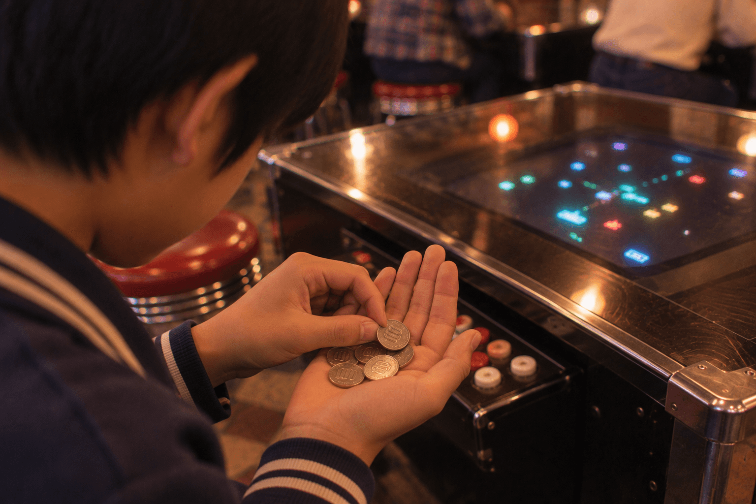 ゲームセンターの入口で100円玉を握りしめる子どものイメージ